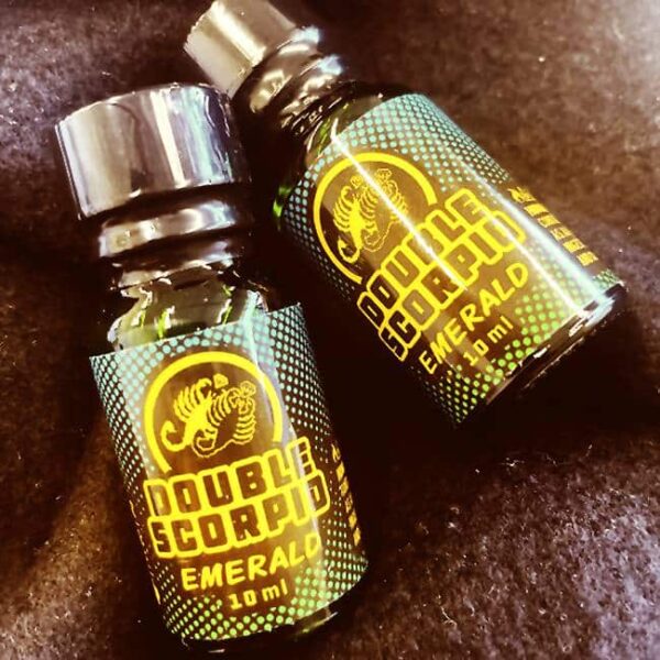 Two small bottles of double scorpio emerald - 10ml labeled product on a dark textured background.